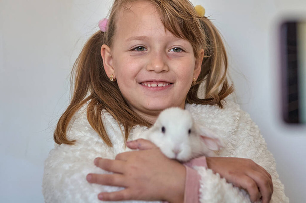 blonde girl with a white rabbit in her arms - Foto, Imagen