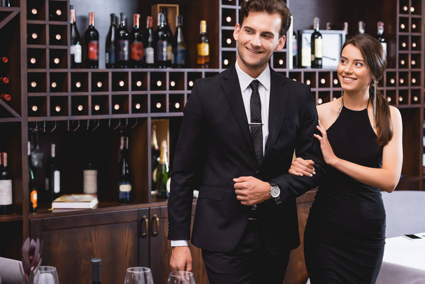 Selective focus of elegant woman touching hand of boyfriend in formal wear in restaurant  - Фото, зображення