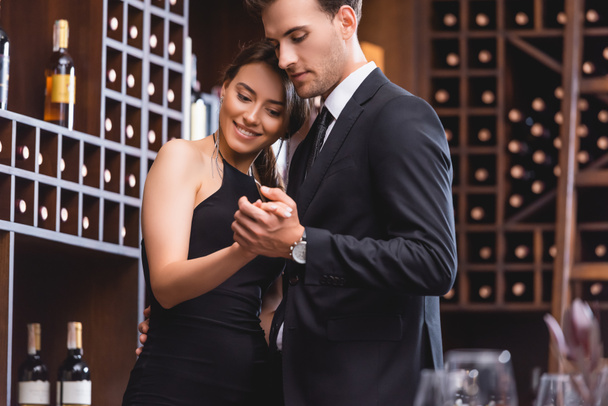 Selective focus of young man in suit dancing with elegant girlfriend in restaurant  - Фото, зображення