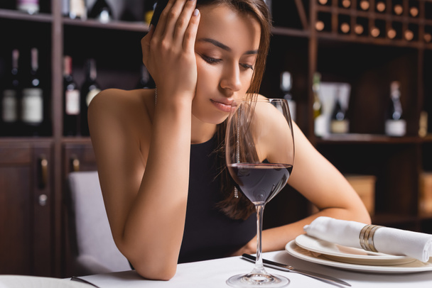 Triste femme regardant un verre de vin à table au restaurant  - Photo, image