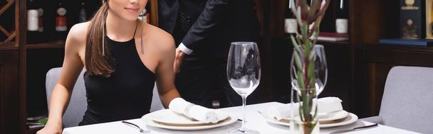 Poziomy obraz mężczyzny stojącego obok dziewczyny i stołu w restauracji  - Zdjęcie, obraz