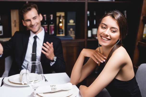 Selectieve focus van jonge vrouw op zoek weg in de buurt van vriendje tijdens het daten in restaurant  - Foto, afbeelding