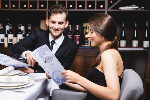 Selective focus of elegant couple looking at menu in restaurant  - Fotó, kép