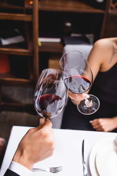 Cropped view of couple toasting with wine during dating in restaurant  - Foto, Bild