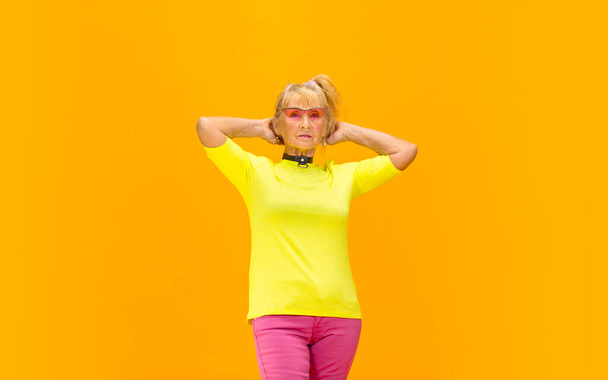 Senior woman in ultra trendy attire isolated on bright orange background - Fotó, kép