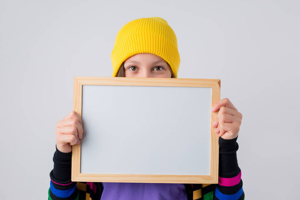 Dospívající dívka drží prázdné kreslicí prkno. Izolované na světle šedém pozadí, koncepce emocí teenagera s kopírovacím prostorem pro text - Fotografie, Obrázek