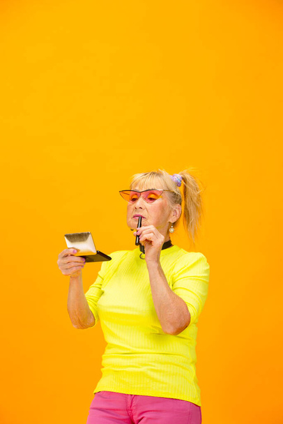 Senior woman in ultra trendy attire isolated on bright orange background - Zdjęcie, obraz