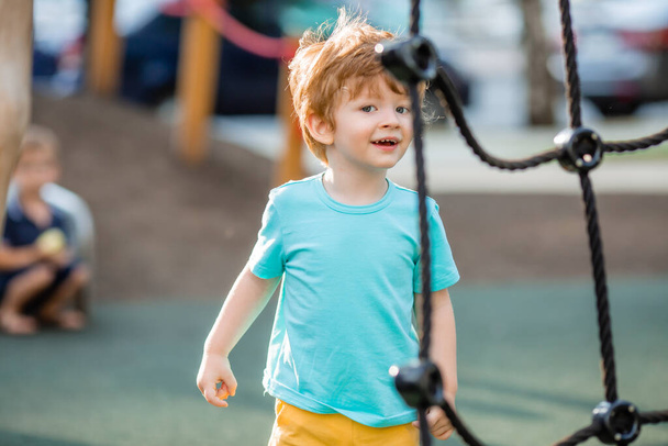 Malý chlapec v modrém tričku tráví čas na dětském hřišti - Fotografie, Obrázek