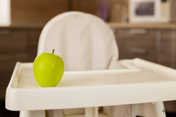 Fehér gyermekszék a konyhában, zöld almával. - Fotó, kép