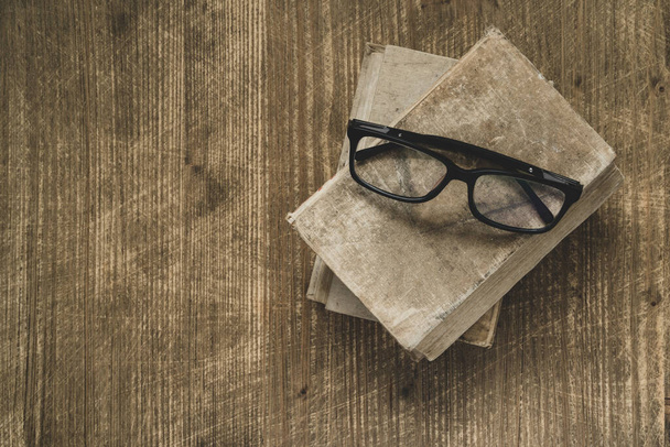 Old books with eyeglasses on wooden table,top view - Valokuva, kuva