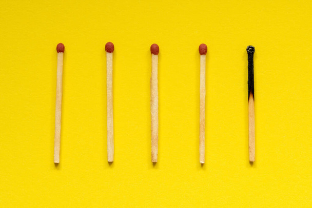 Wooden matches with one burned out on yellow background - Foto, immagini