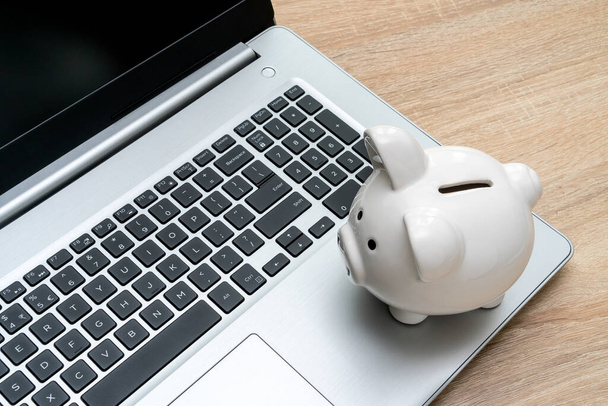 Piggybank on laptop keyboard in money saving concept. Make money online or internet business concepts - Foto, Imagem