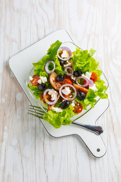 Görög saláta feta sajttal, fekete olajbogyóval és hagymával fehér alapon - Fotó, kép