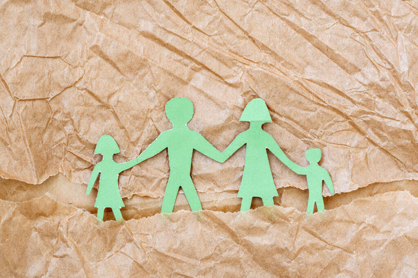 Family with two children, paper figures on a brown paper background - Foto, Imagem