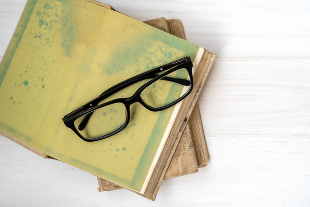 Black eyeglasses on books placed on white wooden background. Top view, copy space. - Valokuva, kuva