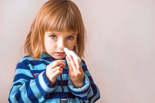 belle petite fille utilise un spray nasal pour les allergies ou les maladies, fond clair, le concept de rhumes et les maladies saisonnières virales - Photo, image