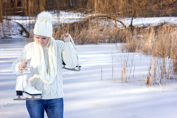 красива молода жінка в зимовому одязі тримає кучеряві білі ковзани в руках зимового пейзажу
, - Фото, зображення