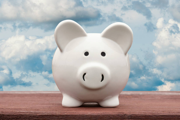 White piggy bank with cloudy sky background. Saving or investment concept - Foto, Imagem