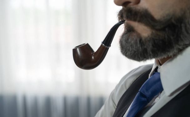 Portrait of vintage business gentleman, white man with mustache and beard, Caucasian person smoking pipe isolated in retro fashion design concept. Studio shot against dark background. - Photo, image