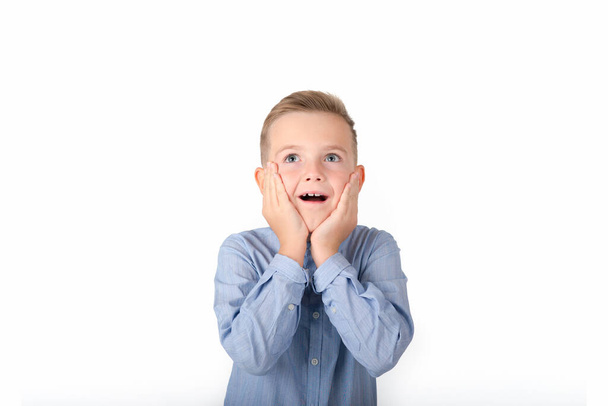 Un chico sorprendido sostiene sus manos en su cara aislada sobre el fondo blanco. - Foto, Imagen