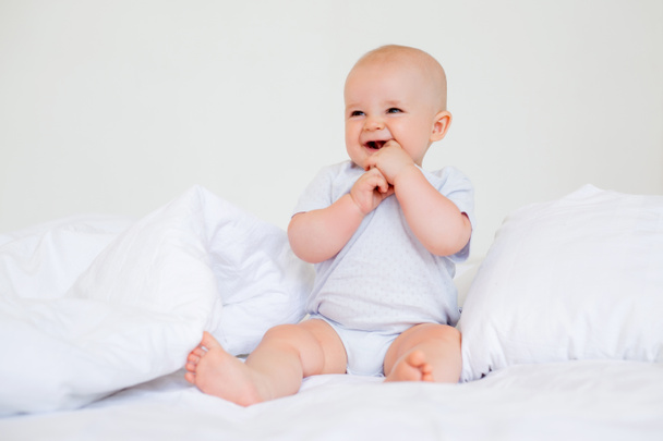 Kuva iloinen vauva poika 6 kuukautta valkoinen kehonpuku sängyssä  - Valokuva, kuva