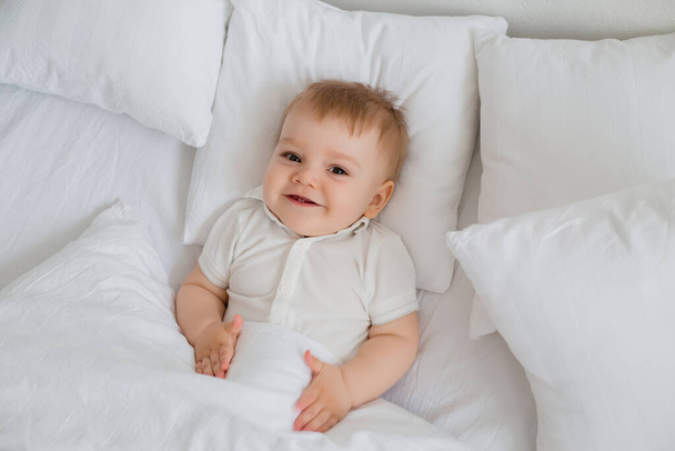 Cute happy little toddler boy laying in bed  - Photo, Image
