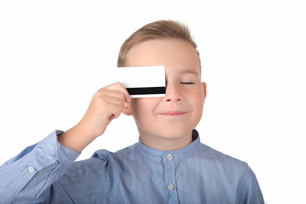 Молодий європеєць, що тримає кредитну картку. Хлопчик закрив очі на біле тло.. - Фото, зображення
