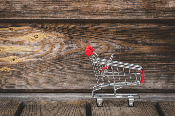 Shopping cart on the wooden floor against wooden wall - Φωτογραφία, εικόνα