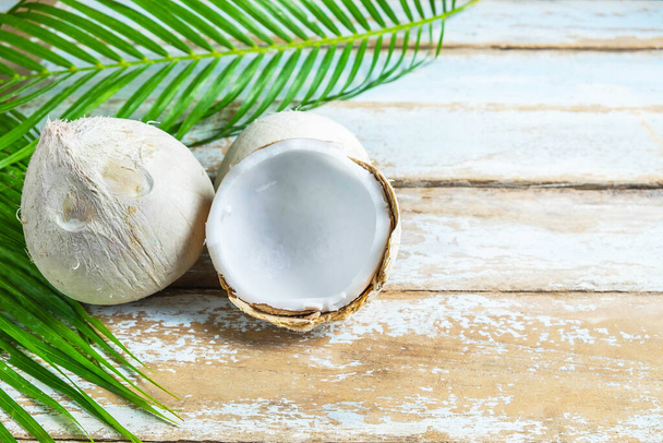 dva kokosové a kokosové listy na dřevěném stole - Fotografie, Obrázek