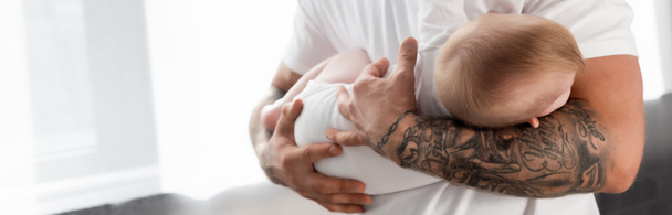 selective focus of tattooed man holding baby boy, horizontal concept - 写真・画像