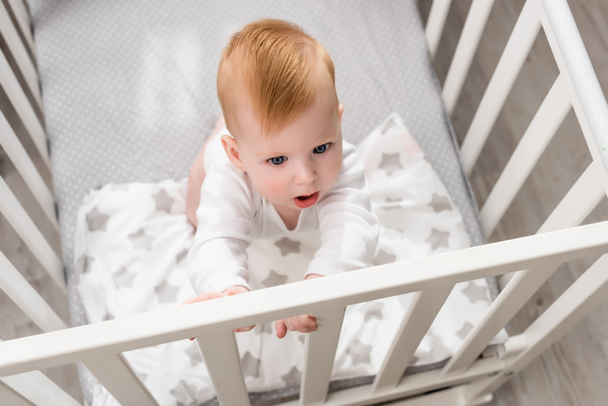 overhead view of infant boy standing in crib - Foto, immagini