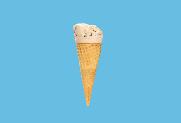 milk tea flavor ice cream cone with some bites on a blue background horizontal composition - Фото, изображение