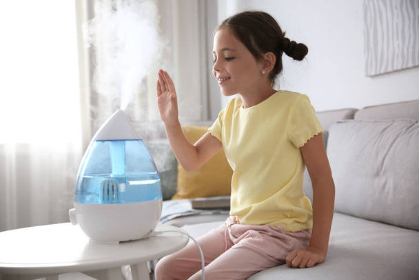 Маленька дівчинка біля сучасного зволожувача повітря вдома
 - Фото, зображення
