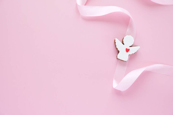Cookies in the shape of an angel with pink ribbon on pink background. - Fotoğraf, Görsel