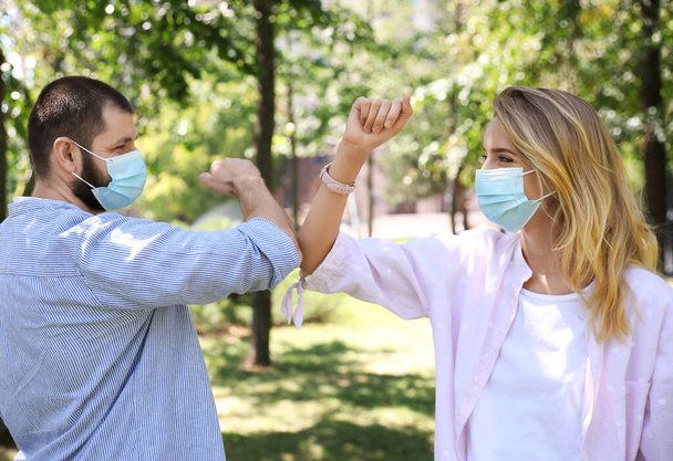 Man and woman bumping elbows to say hello outdoors. Keeping social distance during coronavirus pandemic - Photo, image