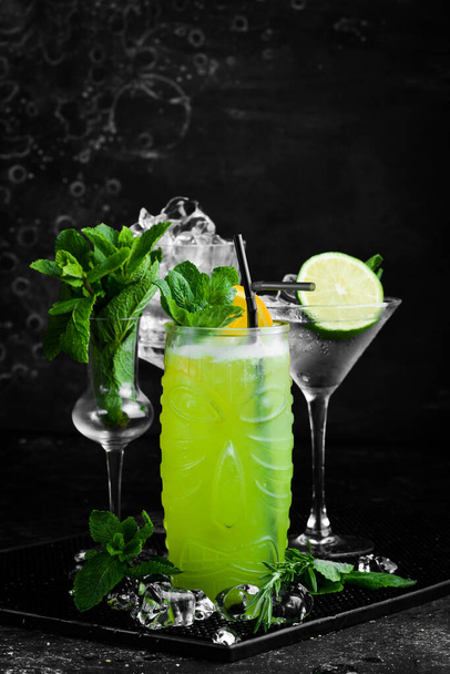 Tropical delicious green alcoholic cocktail - Jungle Juice. On a black stone background. Menu bar. Alcohol. - Foto, Imagen