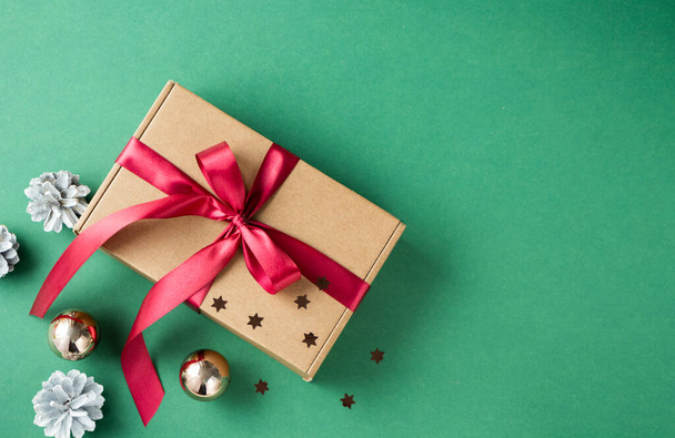 View over brown gift box and red ribbon on a green background. The concept of gifts for the New Year and Christmas. - Photo, image