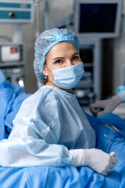 Portrait of the professional female surgeon. Doctor woman wearing mask. Medic near professional equipment. - Photo, Image