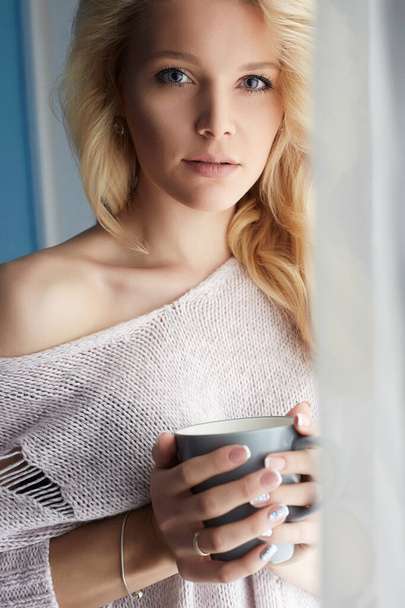 beautiful girl standing at home with a mug of coffee. Winter mood blond woman - Foto, Bild