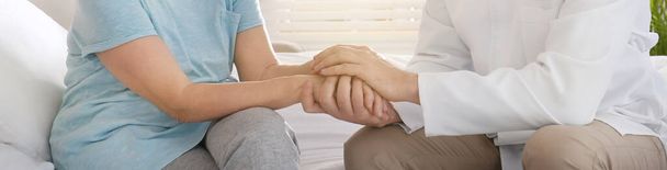 Doctor and senior patient holding hands in hospital, closeup. Banner design - Photo, Image