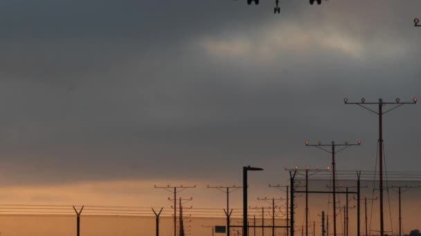 Avión aterrizando en el aeropuerto LAX al atardecer, Los Ángeles, California, EE.UU. Vuelo de pasajeros o silueta de avión de carga, paisaje nublado dramático. Llegada de aviones al aeródromo. Transporte internacional volando - Imágenes, Vídeo