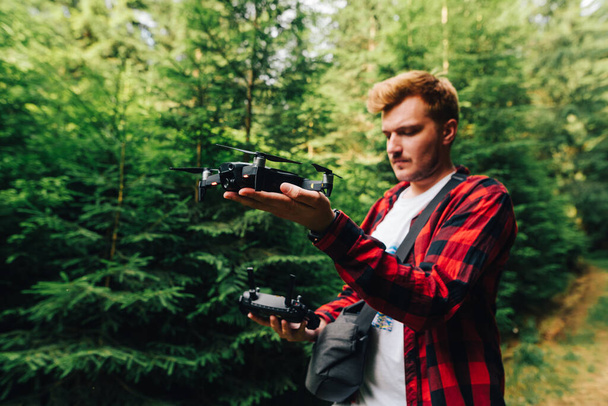 Mladý profesionální samec spustí drone v horském lese nahrávat video z ptačí perspektivy. Mladý muž odpálí dron s rukama v lese. - Fotografie, Obrázek