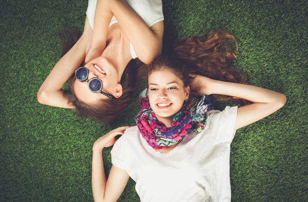 Two pretty girls lying on the fresh green grass - Foto, afbeelding