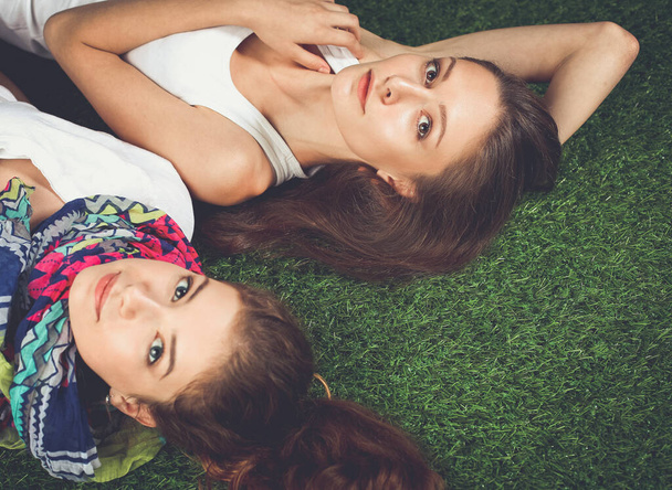 Two pretty girls lying on the fresh green grass - Фото, изображение