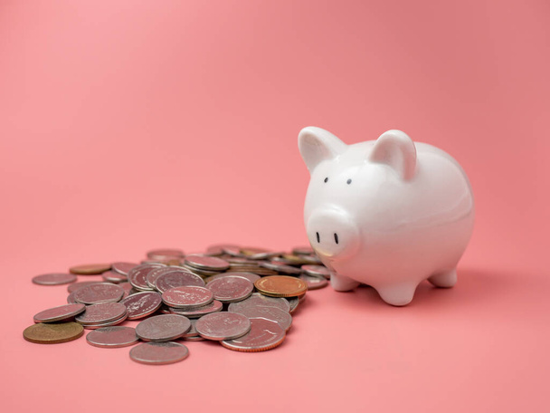 Witte spaarpot met een stapel munten op een roze achtergrond. spaargeld concept. - Foto, afbeelding