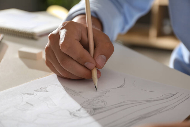 Man drawing portrait with pencil in notepad at table, closeup - Valokuva, kuva