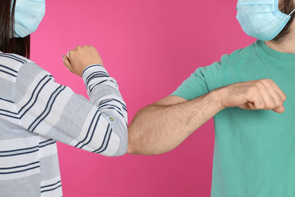 Man and woman bumping elbows to say hello on pink background, closeup. Keeping social distance during coronavirus pandemic - Fotografie, Obrázek