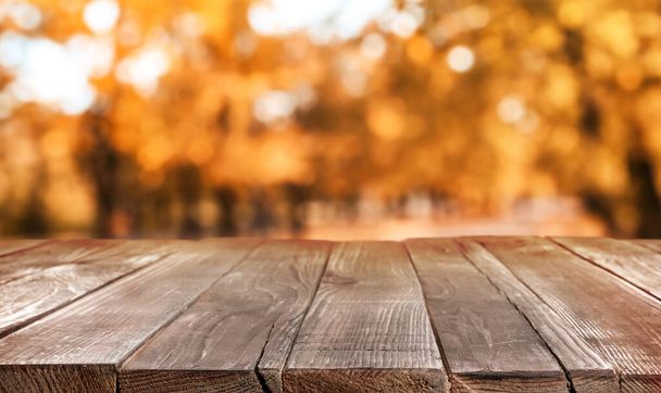 Empty wooden table in beautiful autumn park - Foto, afbeelding