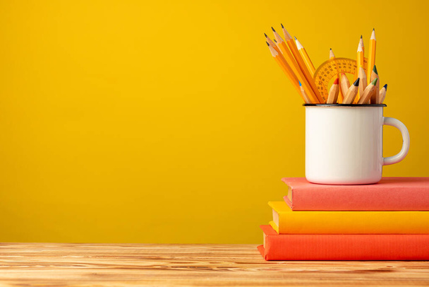 School supplies on wooden desk against yellow background - Фото, зображення