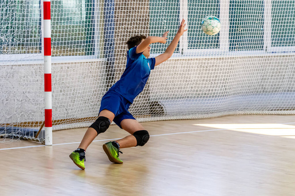 ODESSA, UKRAINE-CIRCA-2020 : Les enfants jouent au mini-football. Futsal gardien de but se tient à la porte. Entraînement sportif des enfants des joueurs de football des gardiens de but de futsal sur le plancher du terrain de football - Photo, image